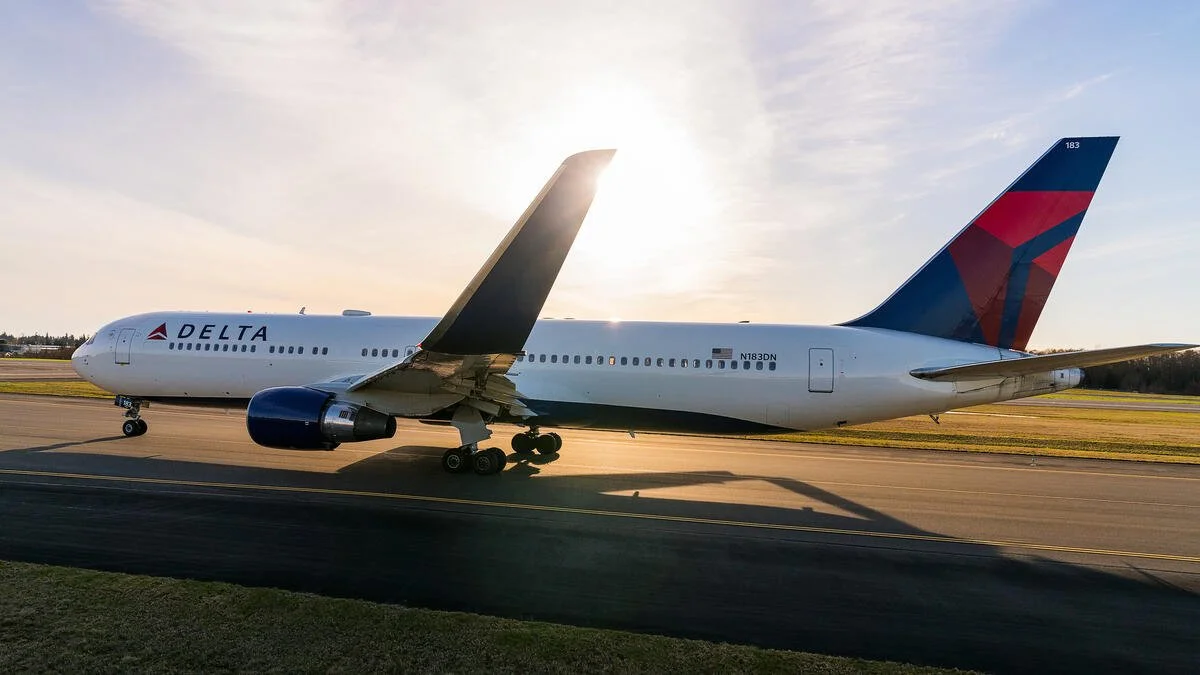 A Delta Airlines airplane parked on the runway at sunset.