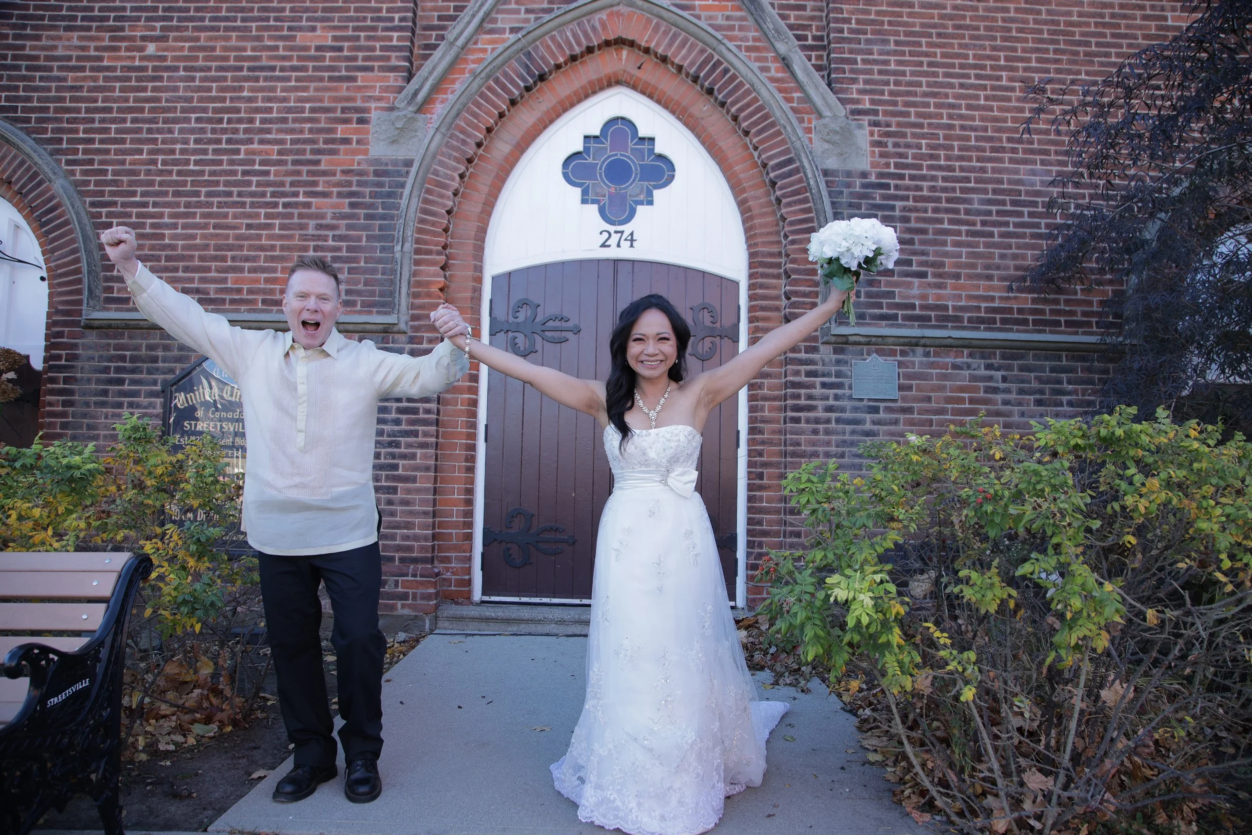 A man and woman in wedding clothes in front of a church building