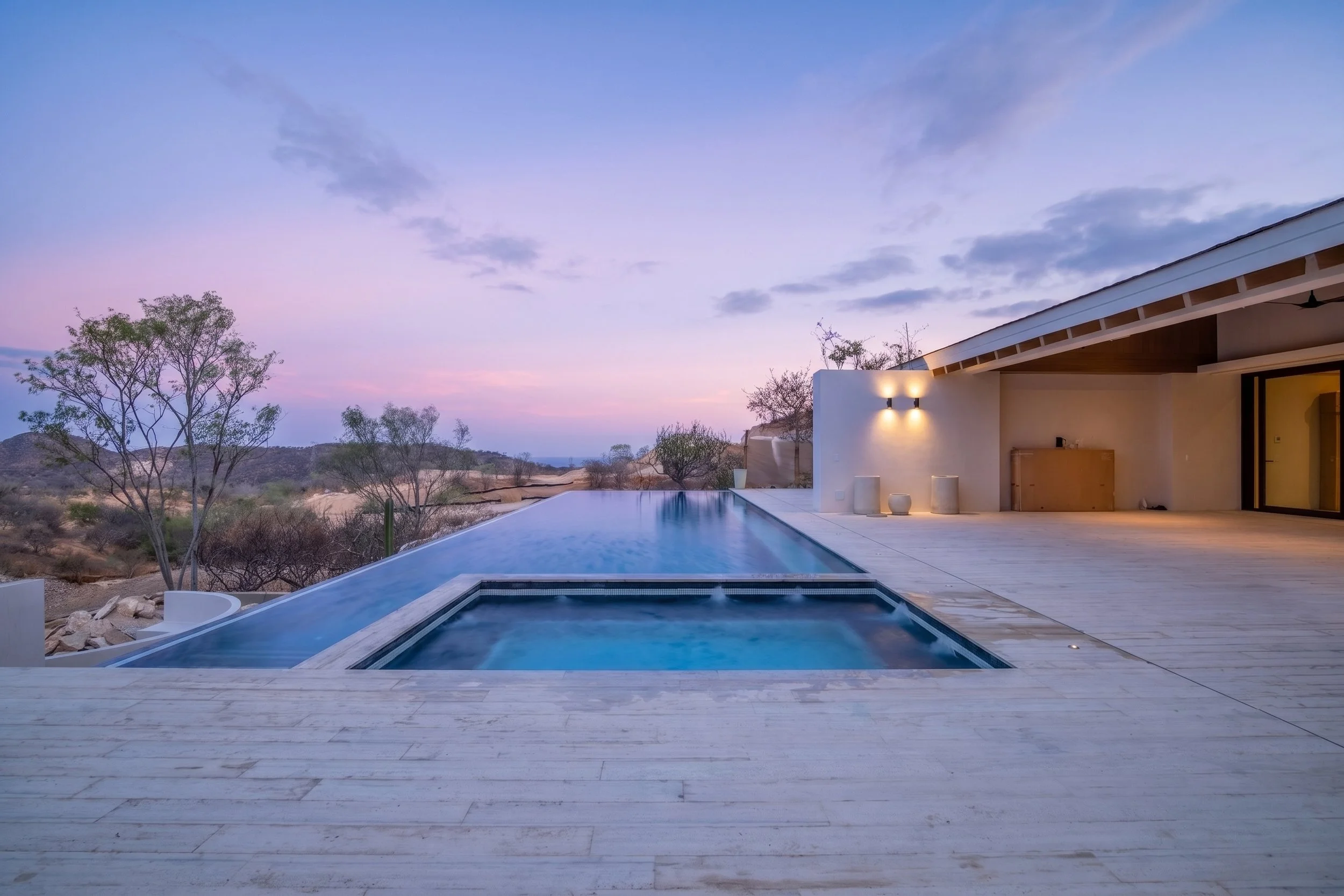 Modern house with outdoor pool overlooking a desert landscape at sunset in Palmilla.
