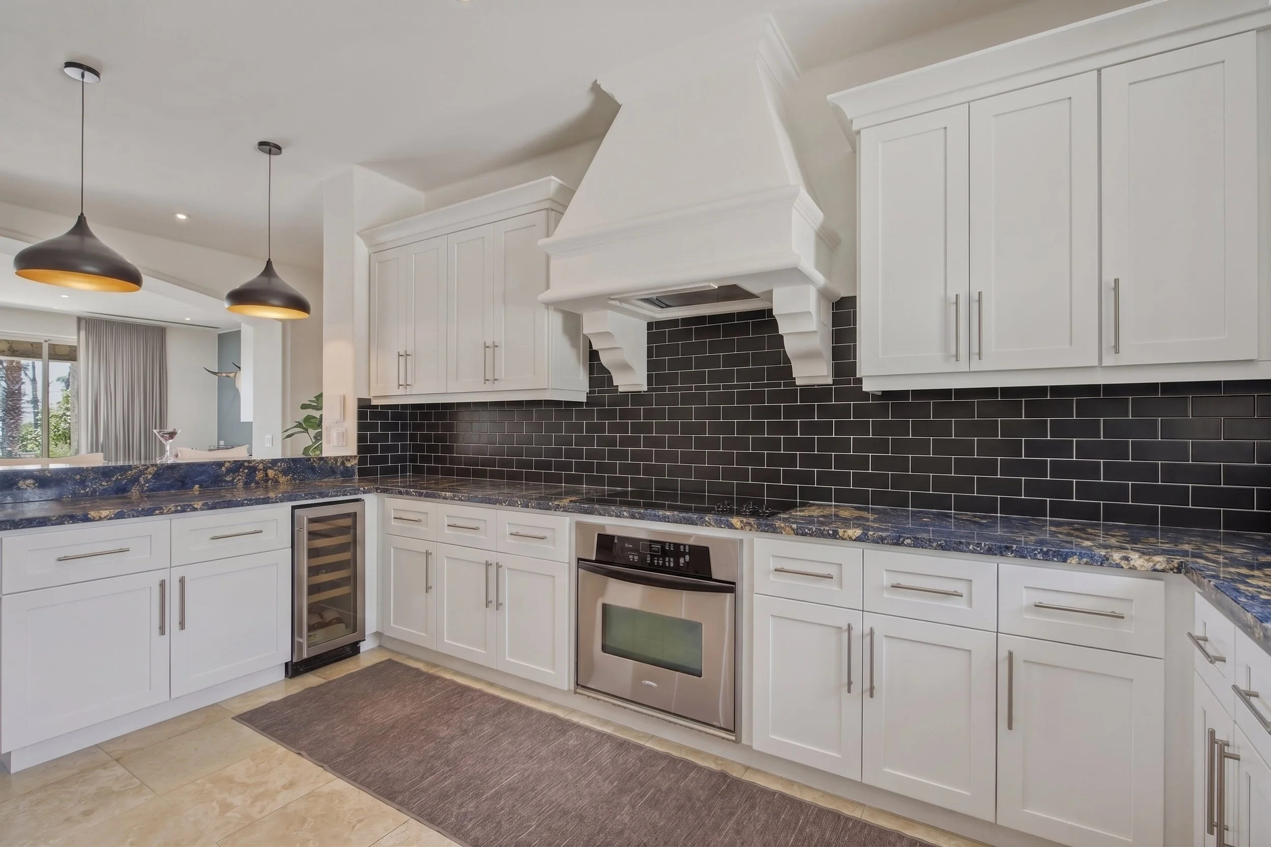 Modern kitchen with white cabinets, black subway tile backsplash, stainless steel appliances, and two black pendant lights.
