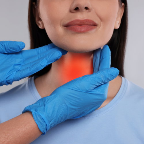 A woman with a sore throat being examined by a healthcare professional wearing blue gloves.