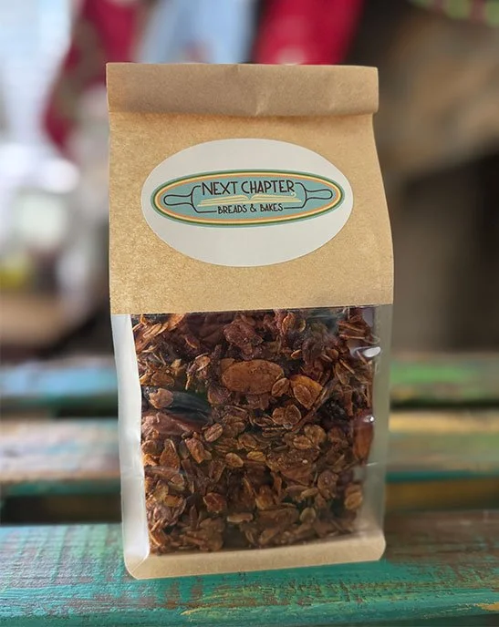 A package of dried chili flakes from Next Chapter Breads & Bakes on a wooden surface.