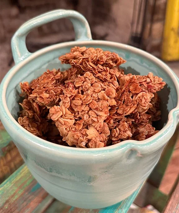 Granola clusters in a light blue ceramic cup on a wooden surface.