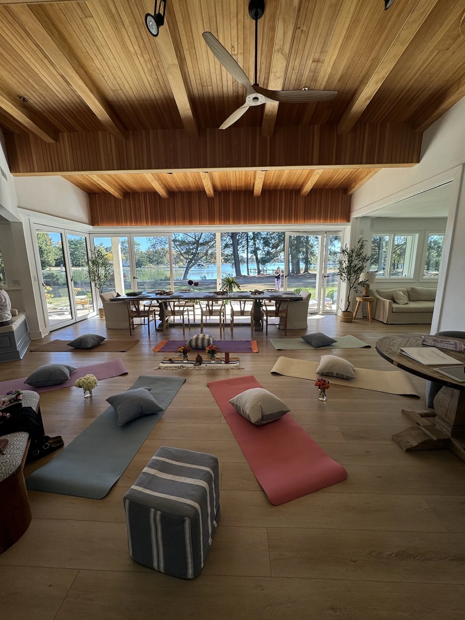 Indoor yoga and meditation class setup for mission-driven organizations in Nevada – spacious room with wooden ceiling, large windows overlooking lake, colorful mats, pillows, and flowers facilitated by ALIGN Agency
