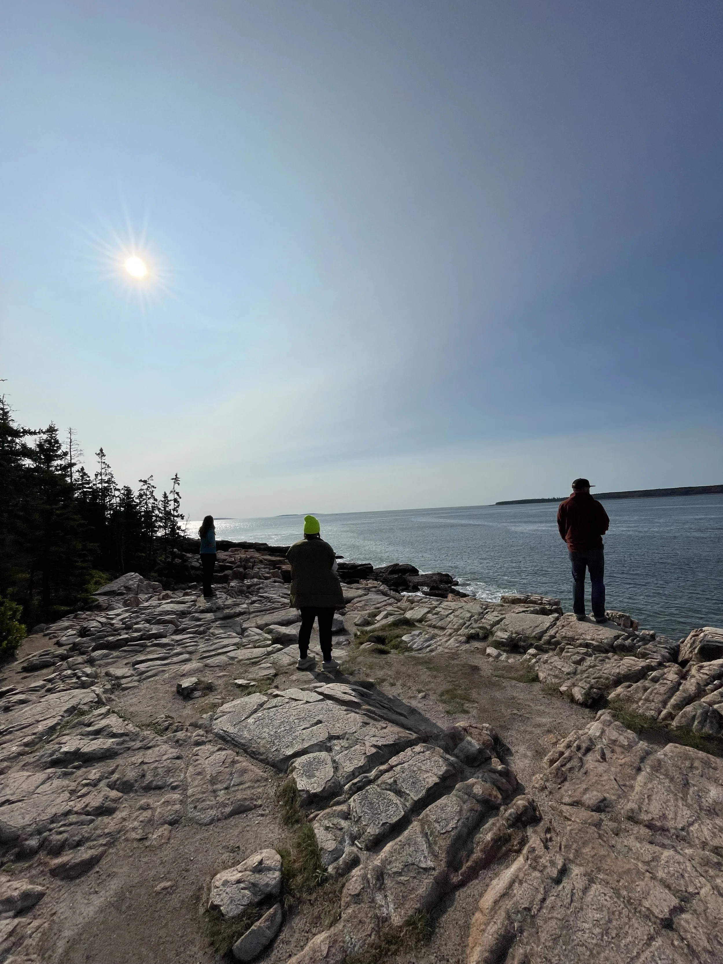 Outdoor wellness or retreat workshop for mission-driven organizations in Nevada – three participants standing on rocky shoreline facing water on clear sunny day, facilitated by ALIGN Agency