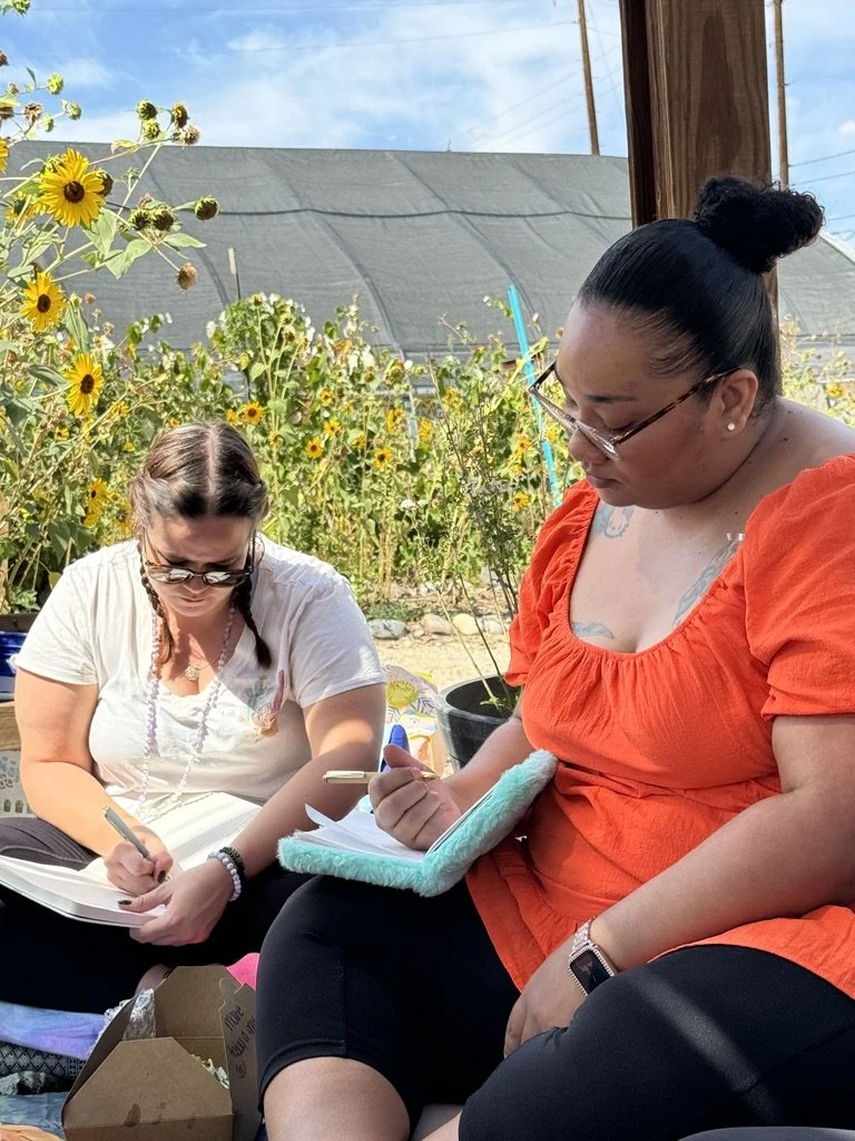 Outdoor creative wellness workshop for mission-driven organizations in Las Vegas – participants journaling near sunflower garden facilitated by ALIGN Agency