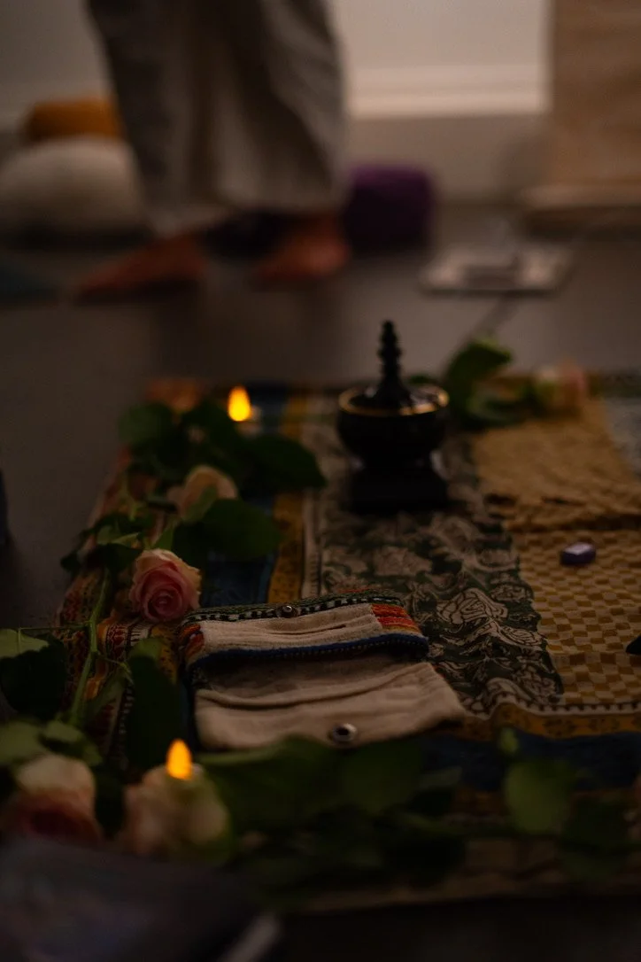 Ceremonial or wellness altar setup for retreat workshop with mission-driven organizations in Nevada – close-up of altar with roses, candles, cloths, and small objects, person standing in background, facilitated by ALIGN Agency
