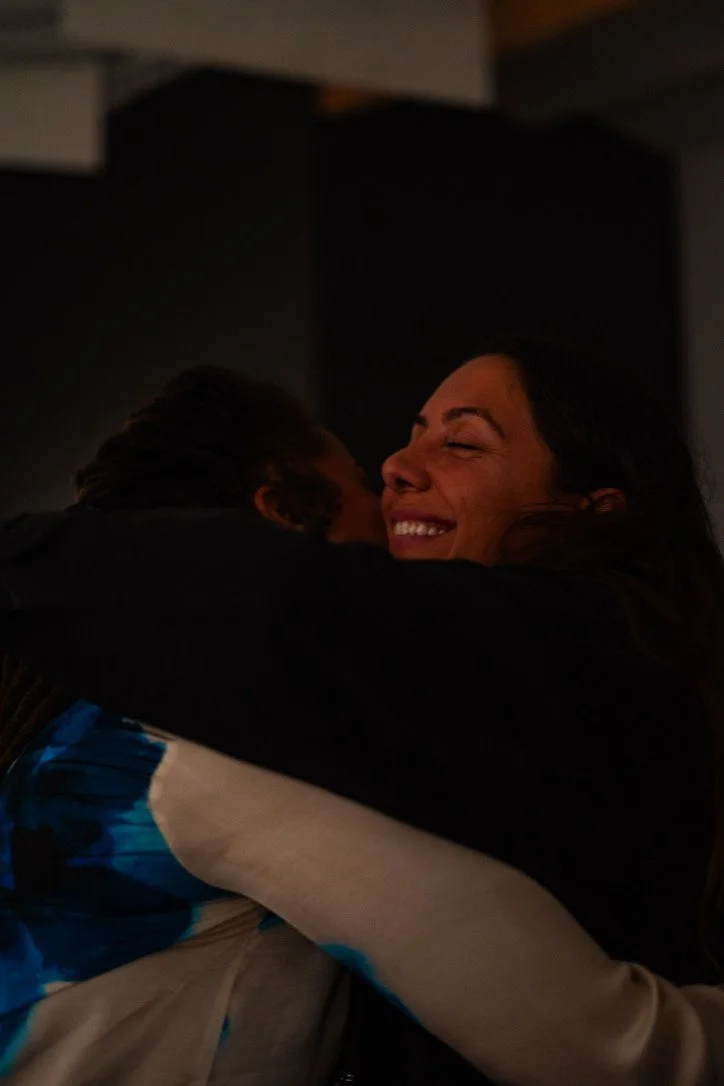 Indoor wellness or retreat workshop for mission-driven organizations in Nevada – woman smiling and hugging another person in dimly lit room, facilitated by ALIGN Agency