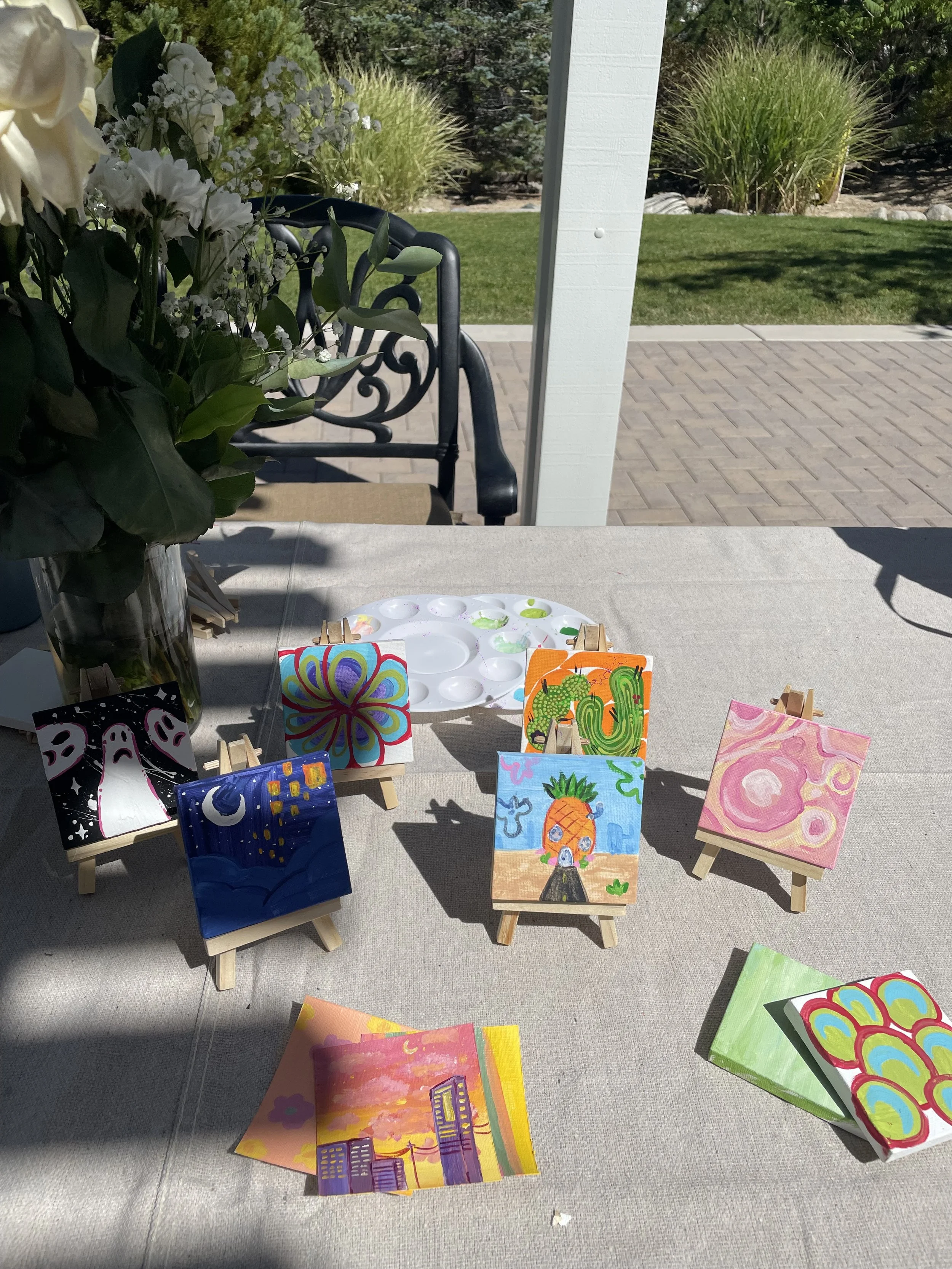 Outdoor creative wellness workshop for mission-driven organizations in Nevada – table with small colorful paintings on mini easels, paint palette, and floral arrangement, facilitated by ALIGN Agency