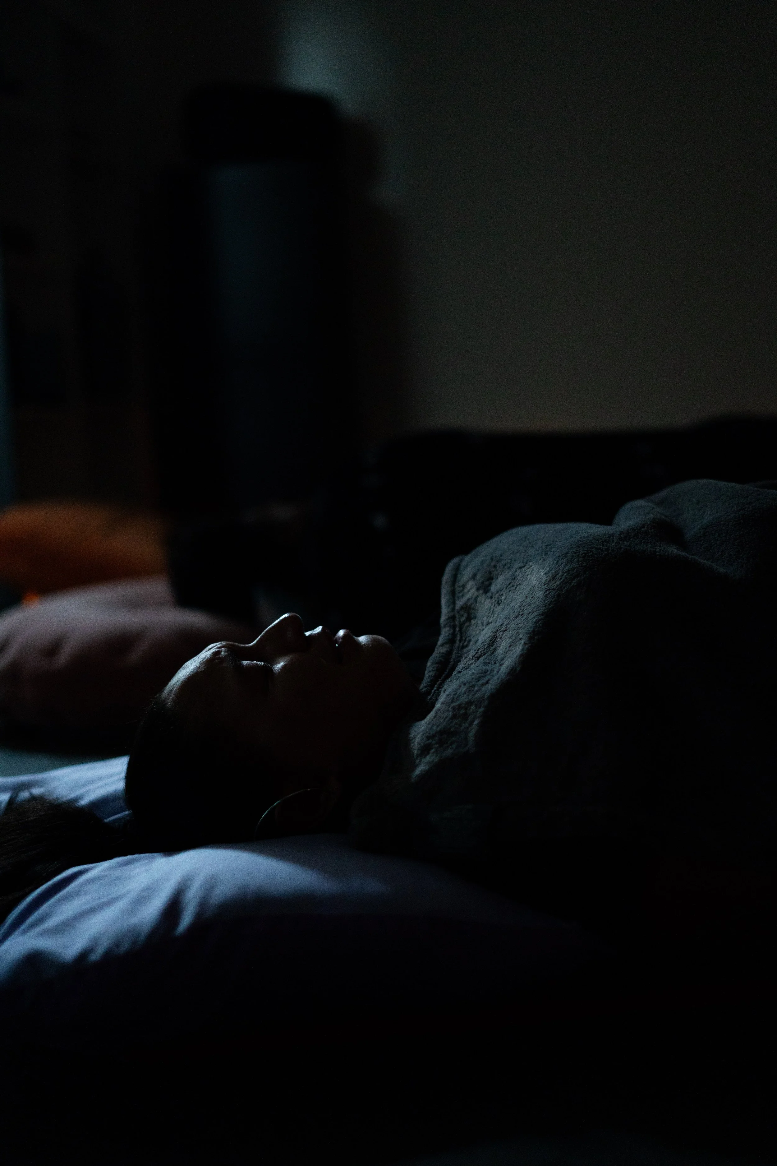 Trauma-informed wellness or meditation session for mission-driven organizations in Nevada – person sleeping in dark room with minimal lighting highlighting their face, facilitated by ALIGN Agency
