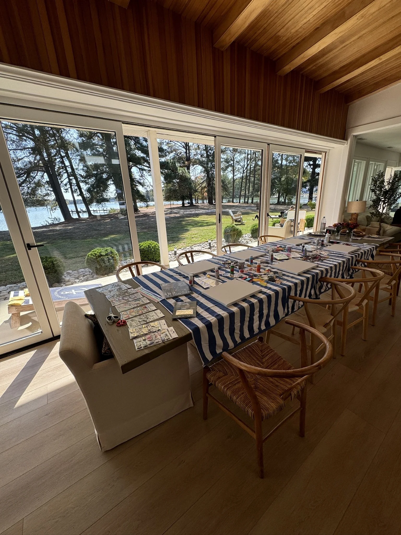 Indoor creative wellness workshop for mission-driven organizations in Nevada – dining table set with art supplies near large windows overlooking lake and trees, facilitated by ALIGN Agency