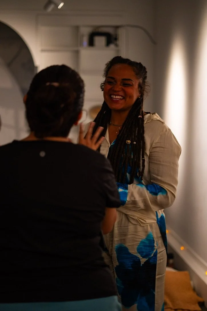 Indoor wellness or coaching workshop for mission-driven organizations in Nevada – two women chatting, one with dreadlocks smiling brightly, the other seen from back gesturing, facilitated by ALIGN Agency
