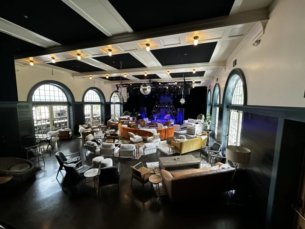Indoor wellness or community event space for mission-driven organizations in Nevada – lounge with large arched windows, assorted sofas and chairs, stage with lighting, and disco ball, facilitated by ALIGN Agency