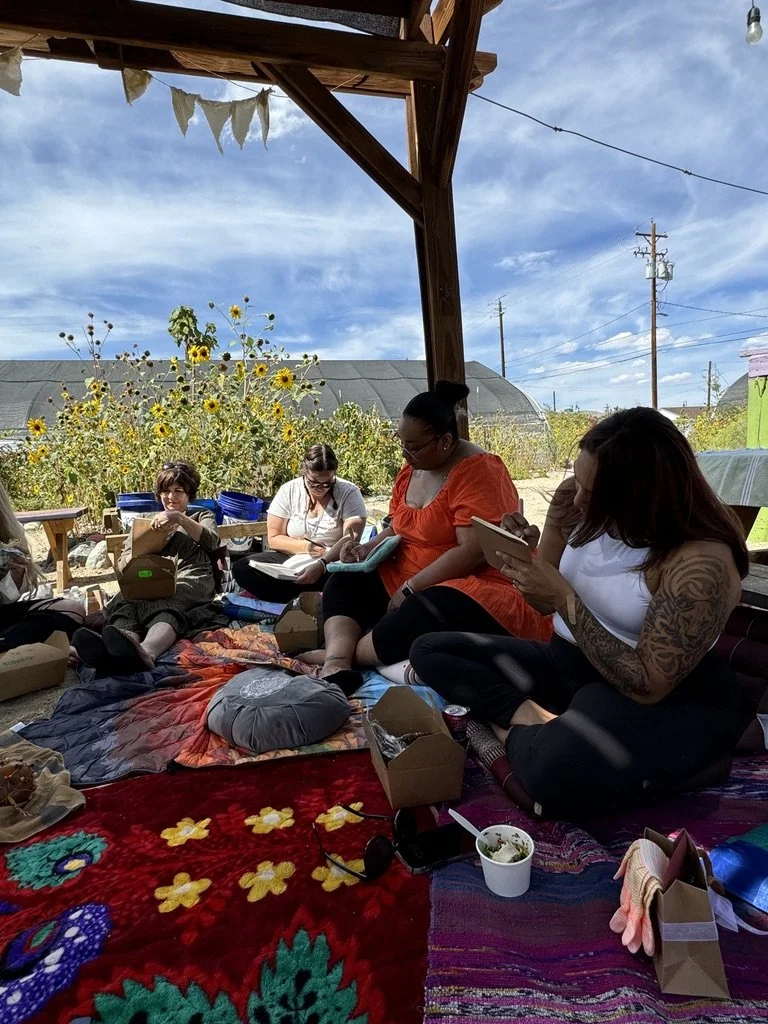 Outdoor creative wellness workshop for mission-driven organizations in Las Vegas – participants using tablets and enjoying meals on sunflower-filled patio facilitated by ALIGN Agency