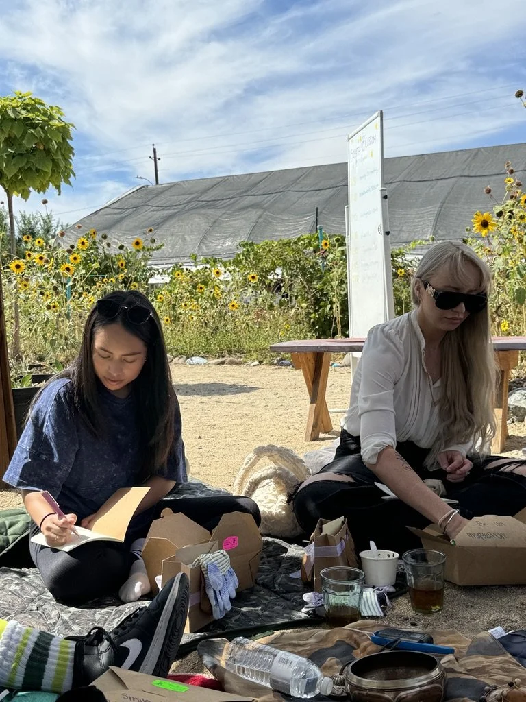 Outdoor creative wellness workshop for mission-driven organizations in Las Vegas – participants journaling and connecting in a sunflower-filled park facilitated by ALIGN Agency