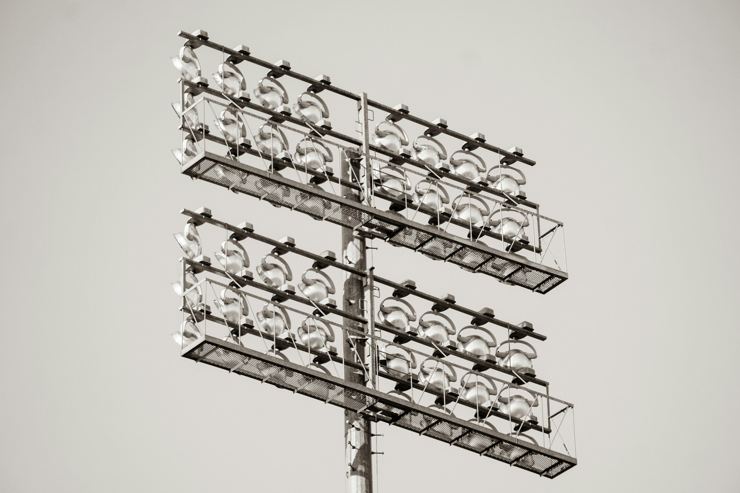A stadium floodlight on a tall pole against a cloudy sky.