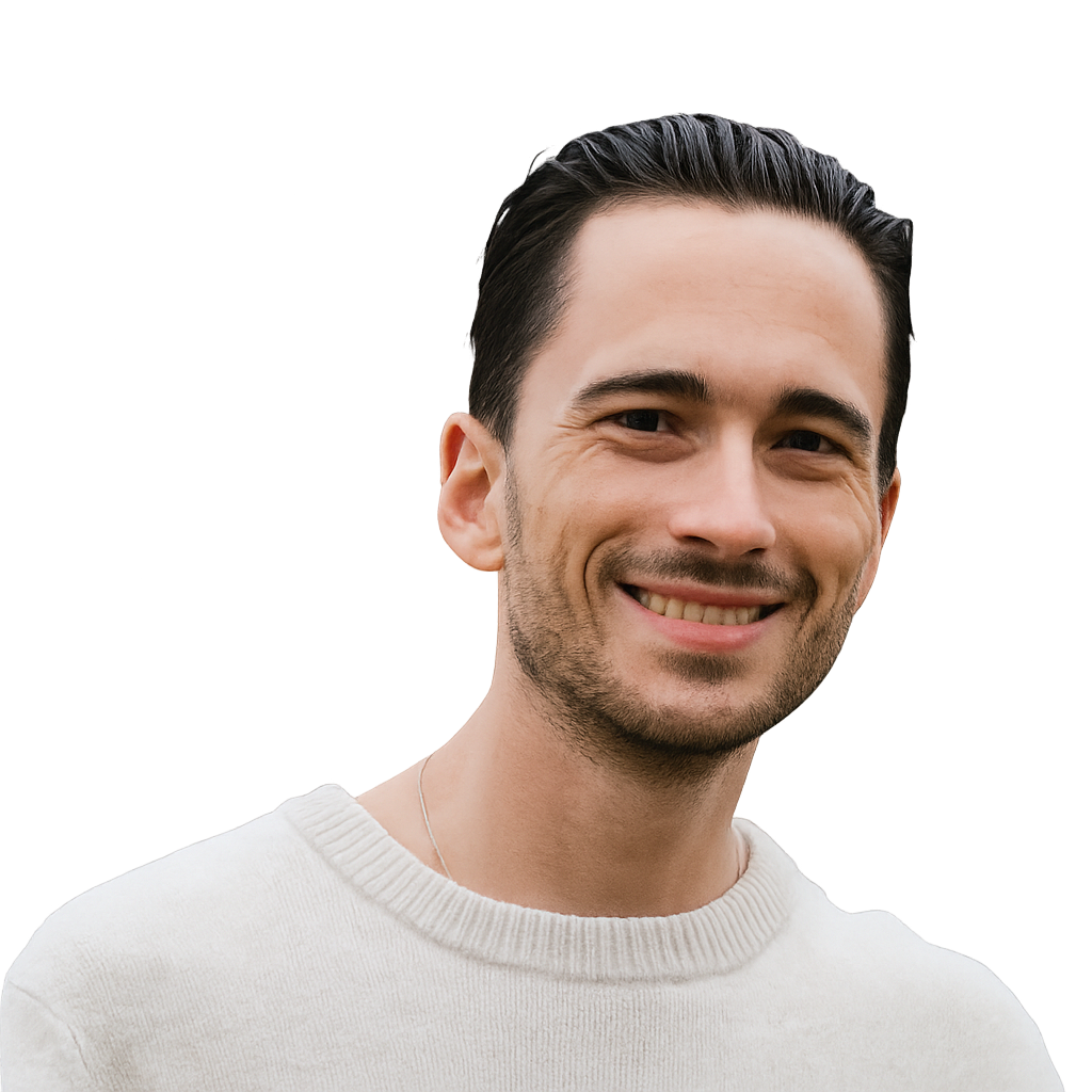 Close-up of a smiling man with dark hair, wearing a white sweater.