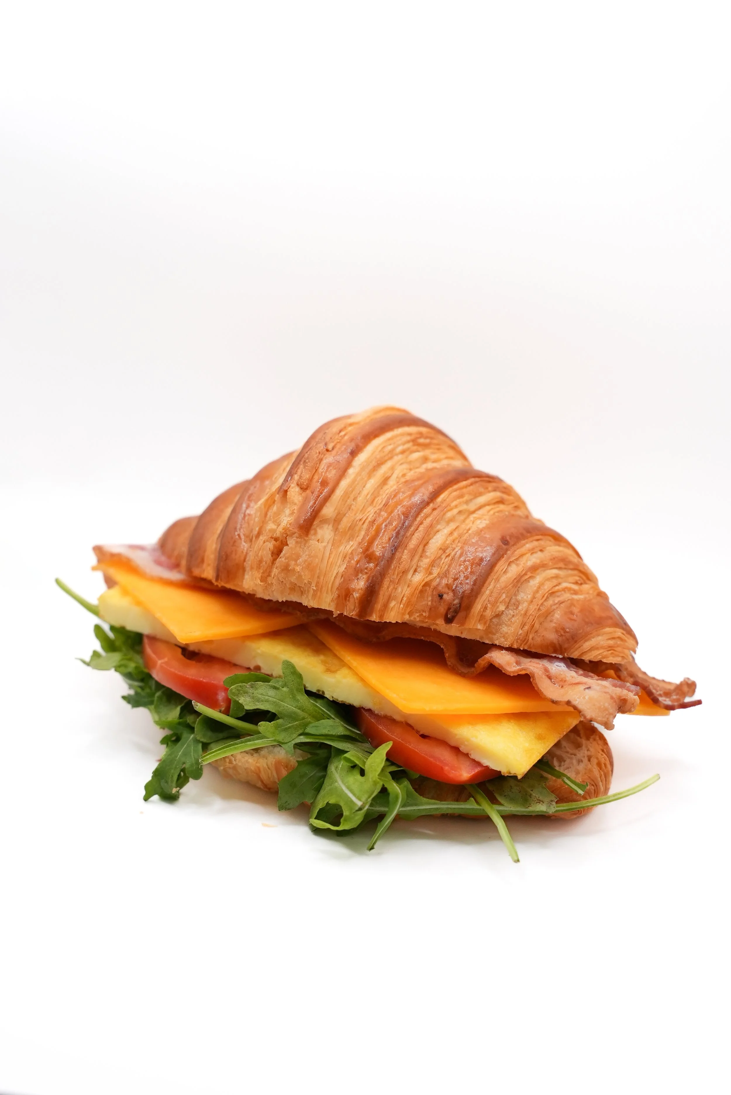 Eggcellent Croissant Honey Cup Coffeehouse Flaky, buttery croissant layered with fluffy egg, crispy bacon, melted cheddar, fresh tomatoes, and peppery arugula