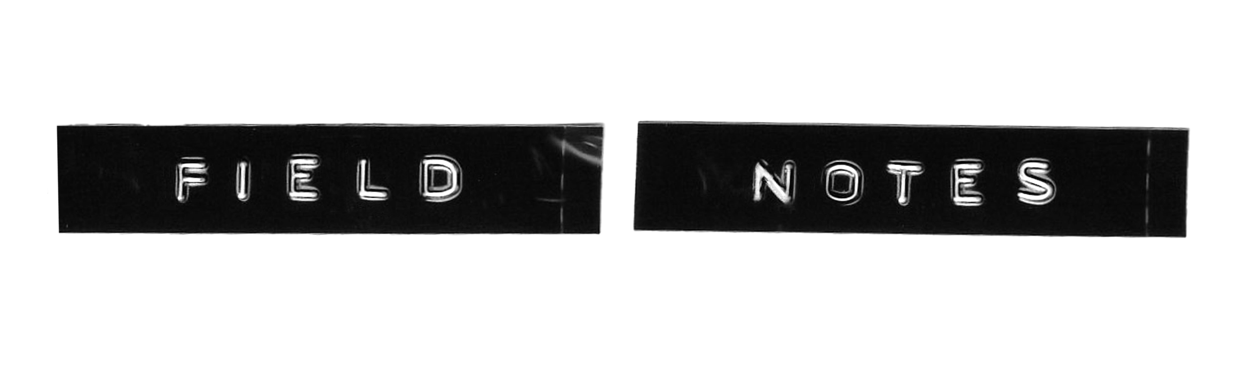 Black and white sign with illuminated letters reading 'FIELD NOTES'.
