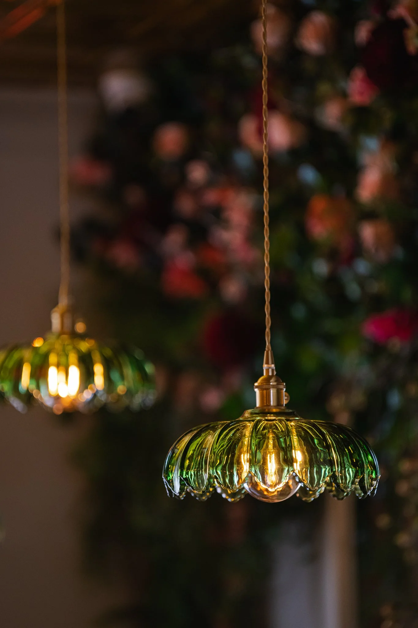 Close-up of a hanging, colorful glass lamp with a blurred background of Christmas decorations and lights.