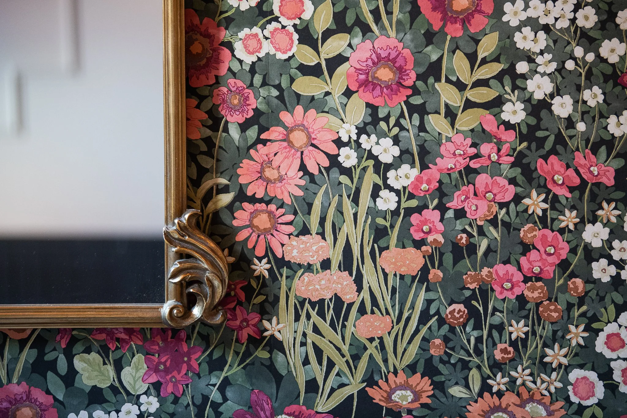 A floral wallpaper with pink, purple, orange, and white flowers and green leaves, bordered by a gold ornate frame on the left side.