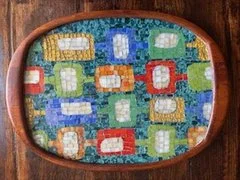 Colorful teak tray with quilt pattern of various geometric patterns on a wooden surface.