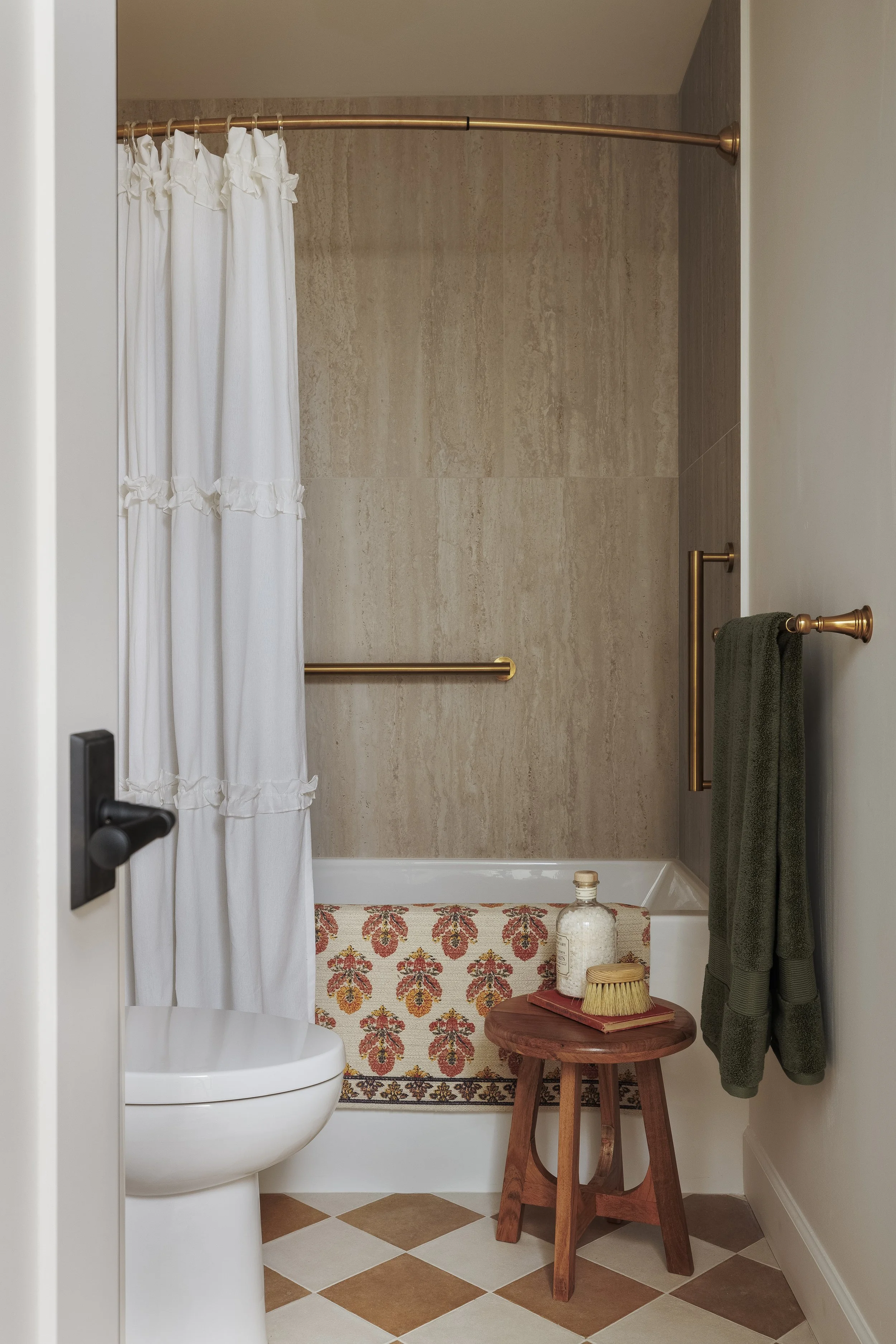 Traditional bathroom with checkerboard floor, travertine tub surround and shabby sheik shower curtain. Interior Design service for Oak Bay and Victoria.
