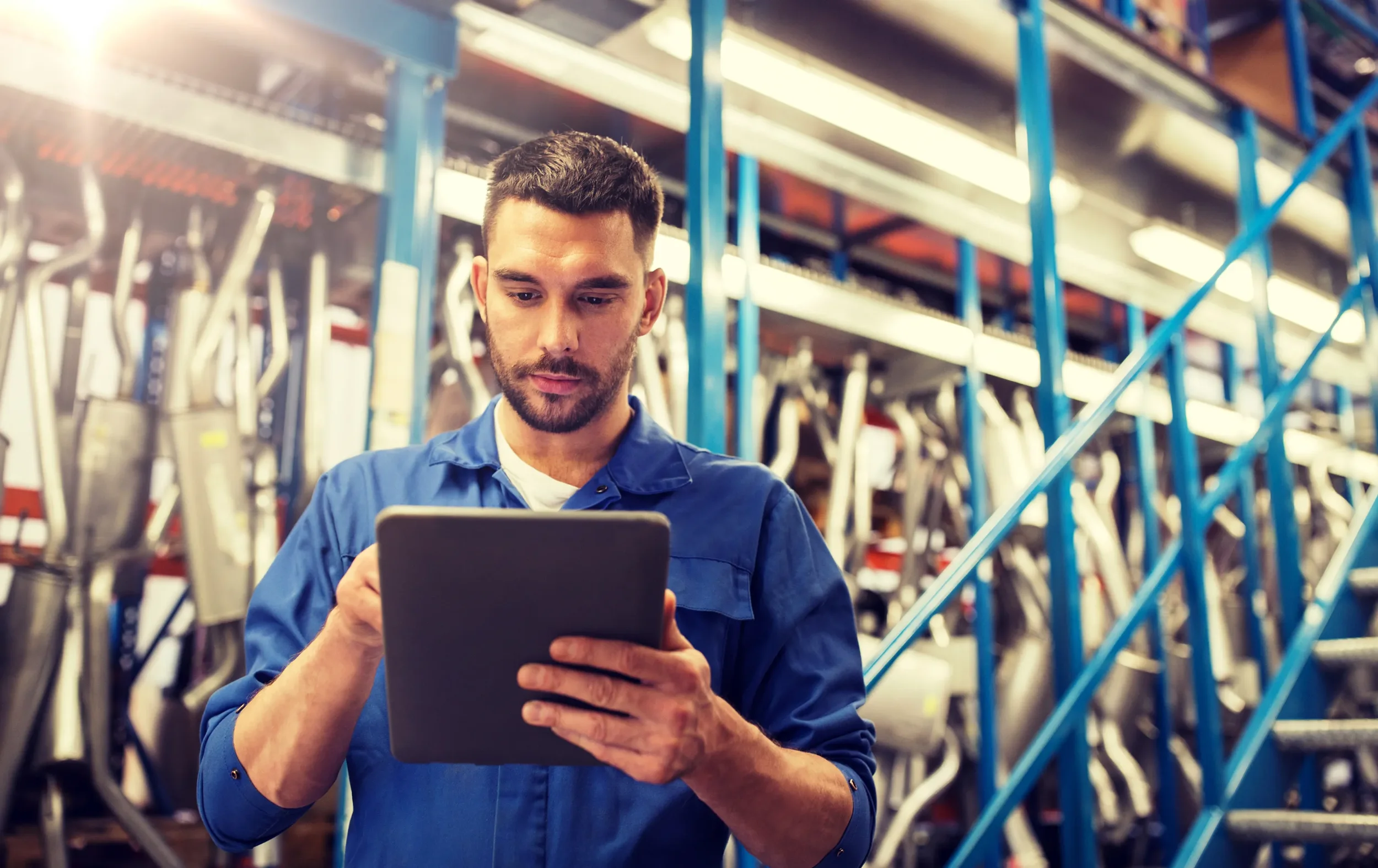 Man in blue work uniform using a tablet in hardware store or warehouse
