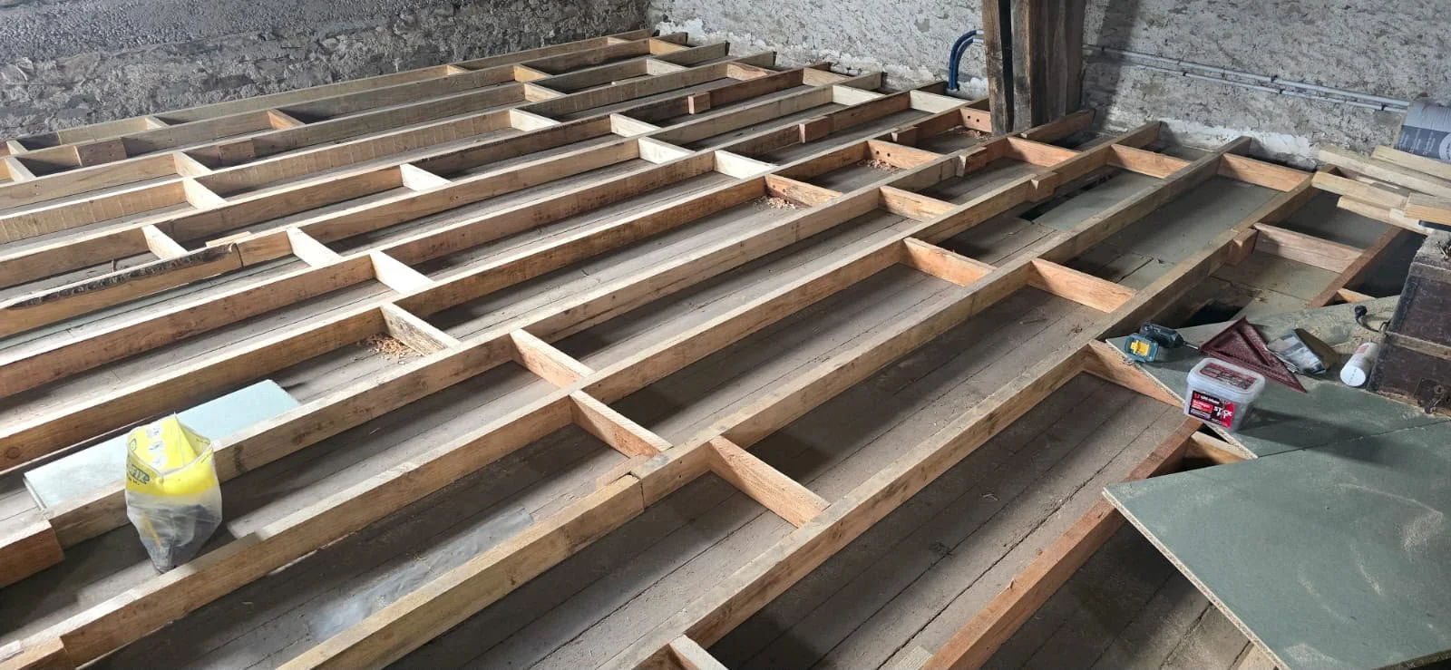 Wooden framework construction on the floor of a building under renovation, with construction tools and materials scattered around.