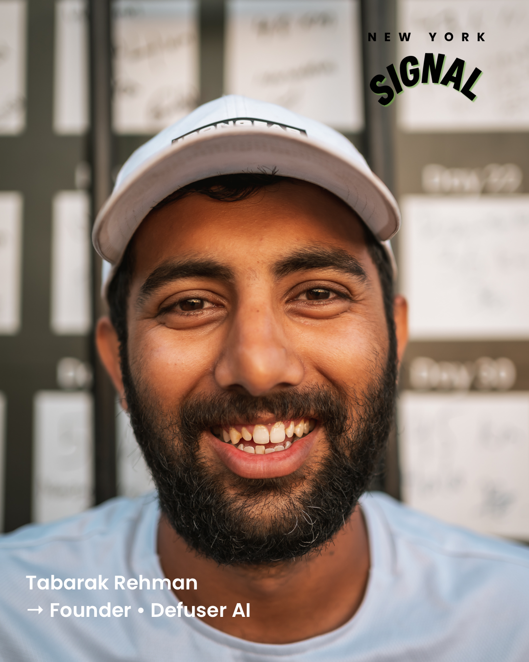 Close-up portrait of Tabarak Rehman, founder of Defuser AI, smiling wearing a white cap, with a blurred background of what appears to be conference or event signage.