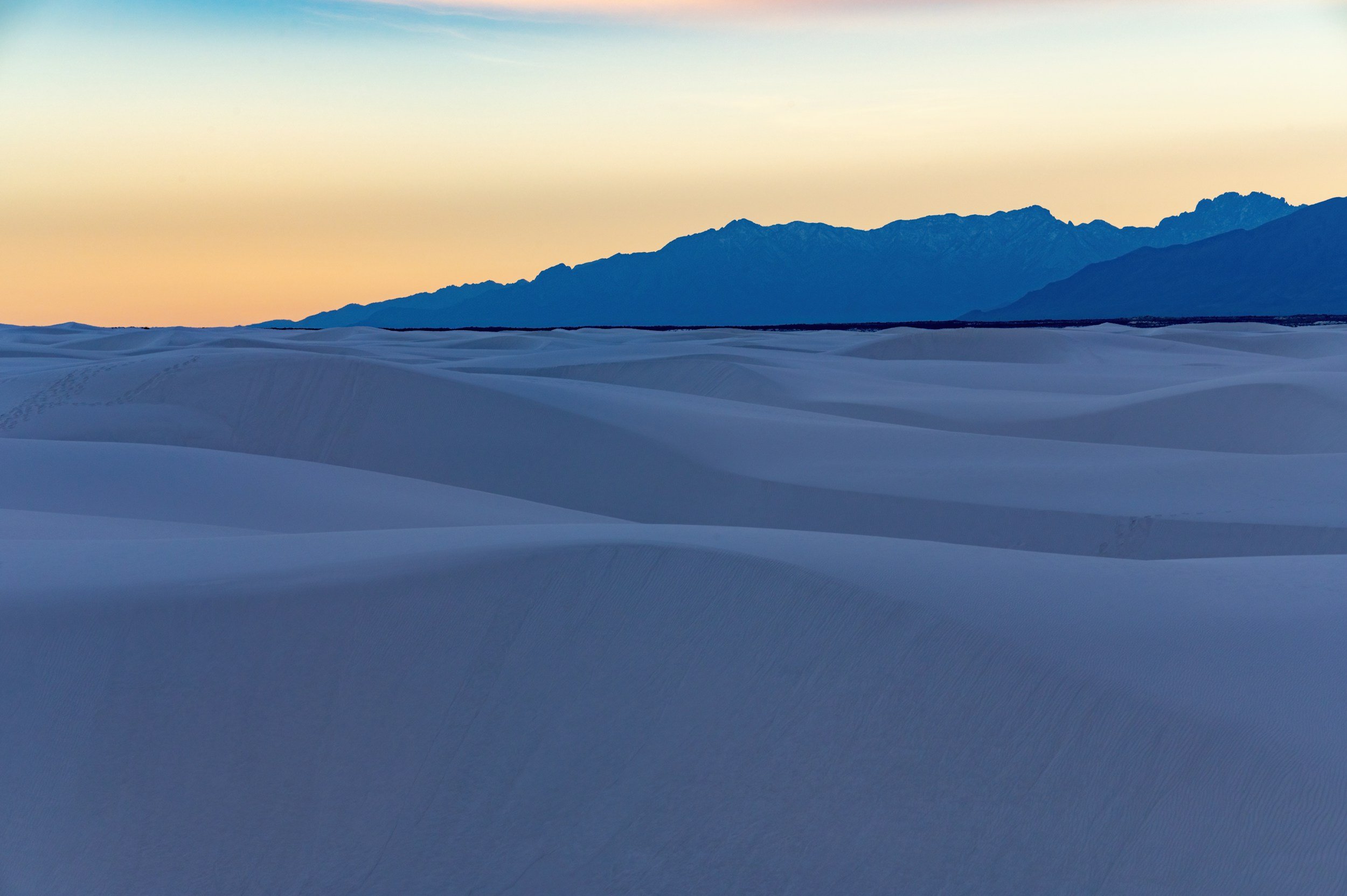 Desert at sunset with sand dunes and mountains in the background