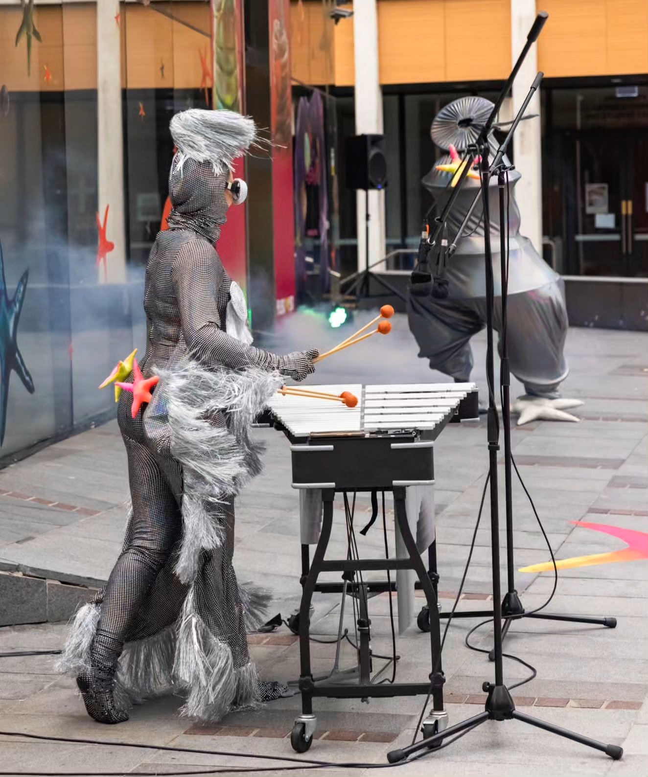 Woman in silver costume playing xylophone outdoors