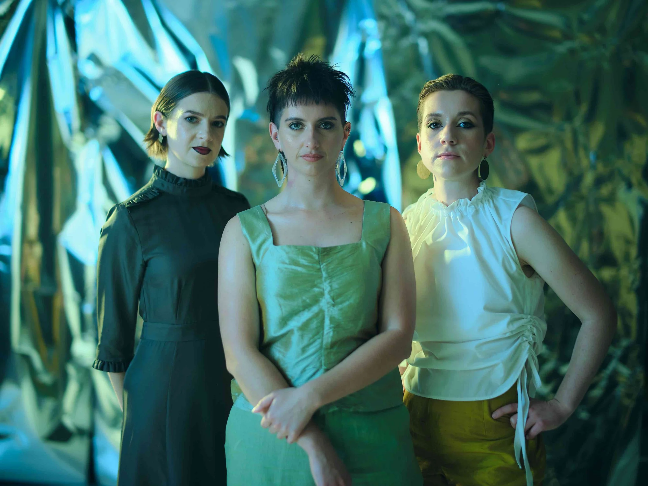 Three woman standing in front of a background of flowing fabric