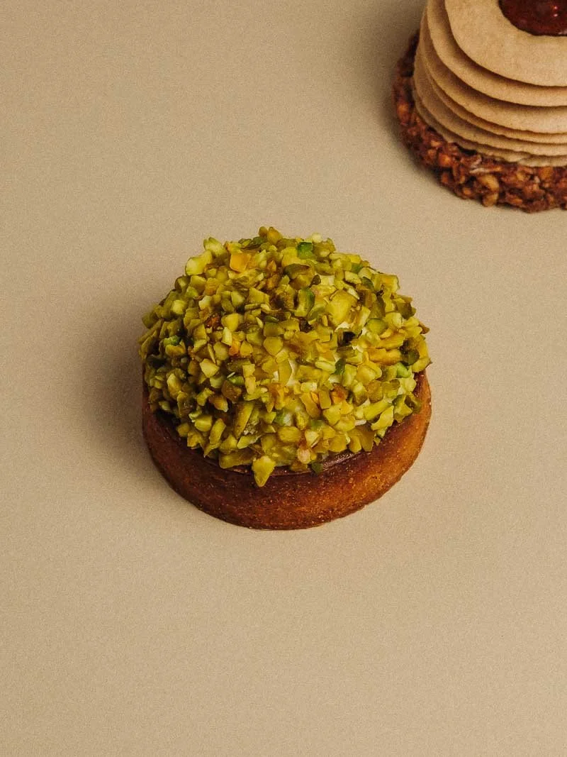Un gâteau avec un dessus recouvert de pistaches hachées.