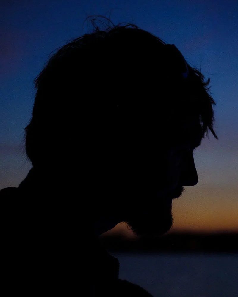 Silhouette d'un homme avec un fond de ciel au crépuscule, couleurs bleu et orange.