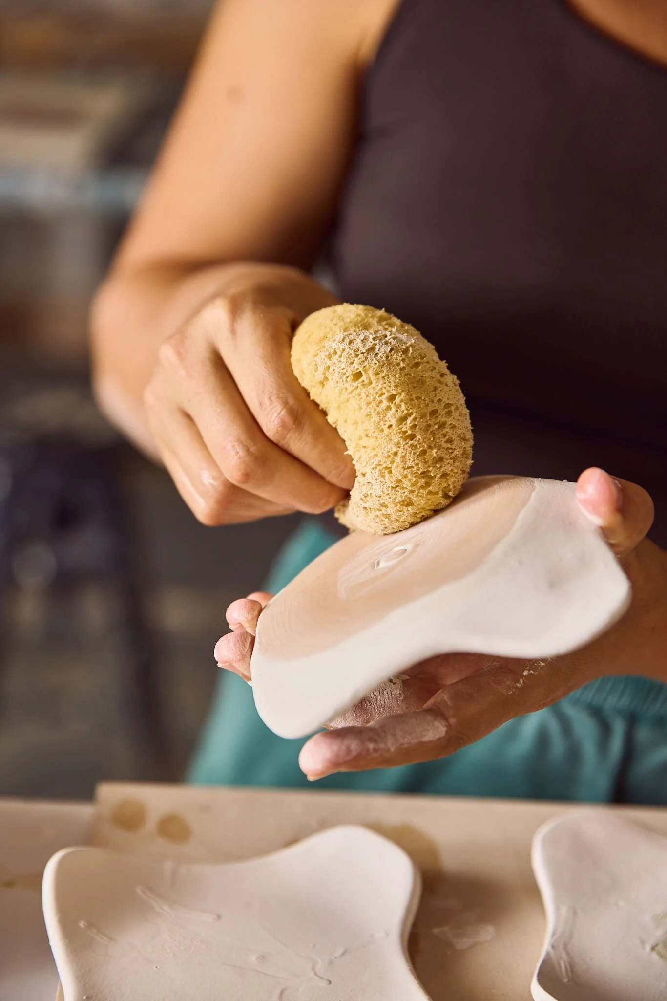 Person cleaning a ceramic sculpture with a sponge in a workshop.