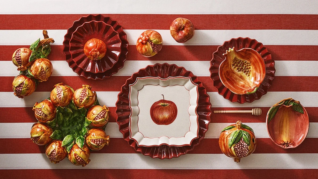 Decorative apple-themed tableware with apples, bowls, and a honey dipper on a red and white striped tablecloth.