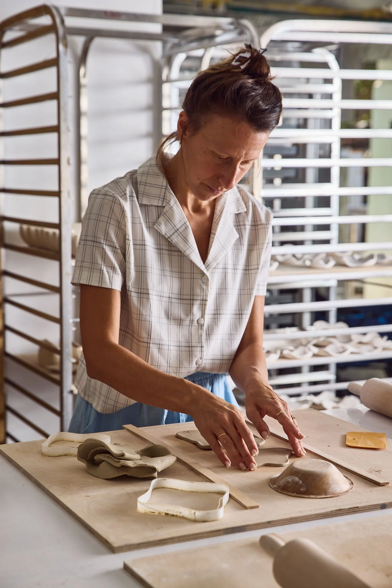 A woman working with clay, shaping pottery on a worktable in a pottery studio.