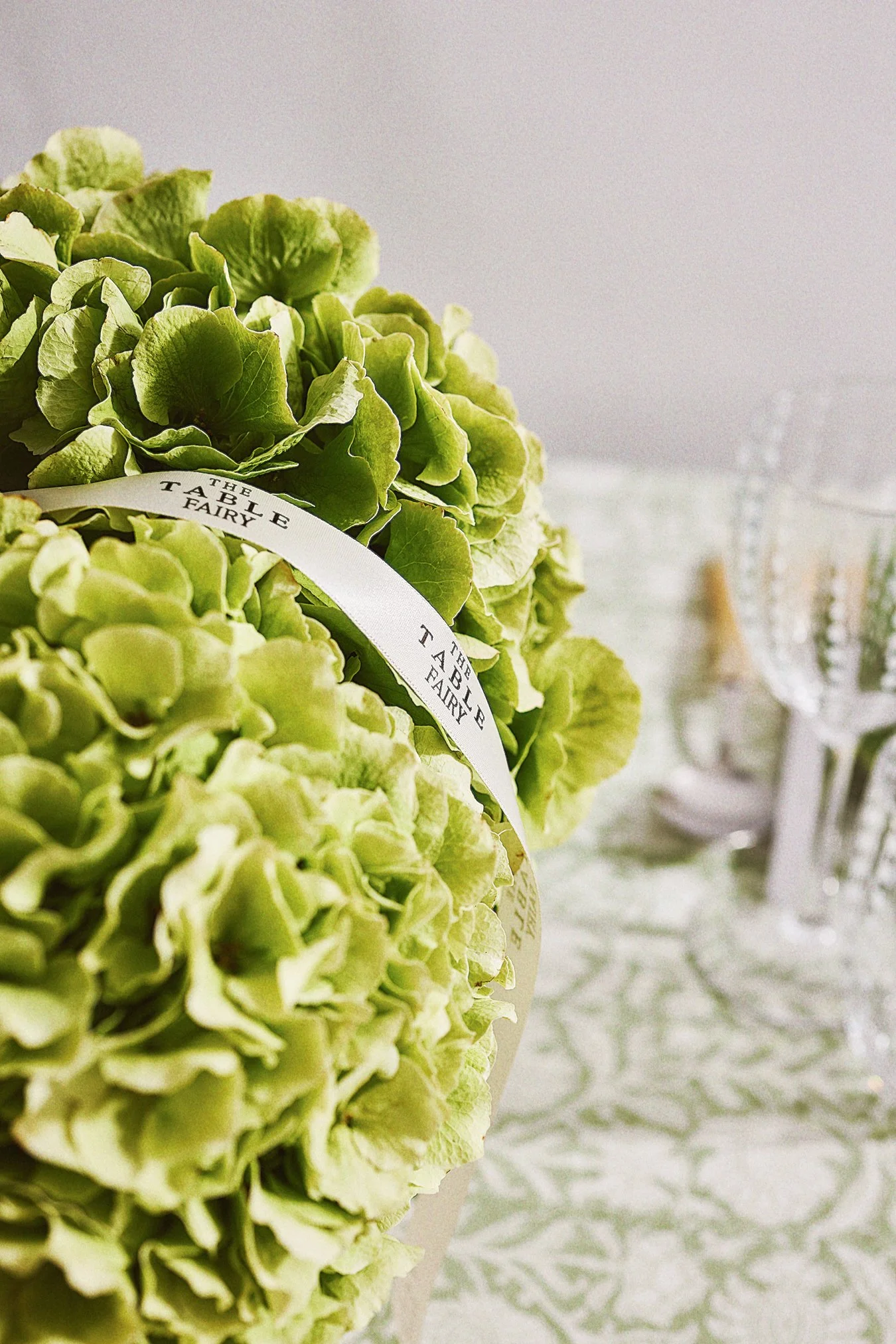 Close-up of light green hydrangea flowers with a white ribbon labeled "The Table Fairy" on a decorated table.