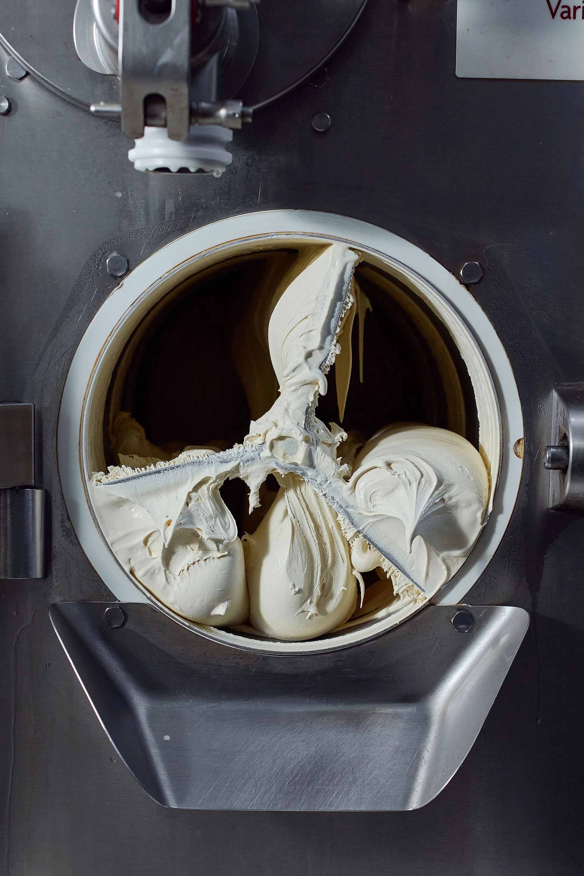 Commercial ice cream maker with creamy vanilla ice cream inside.