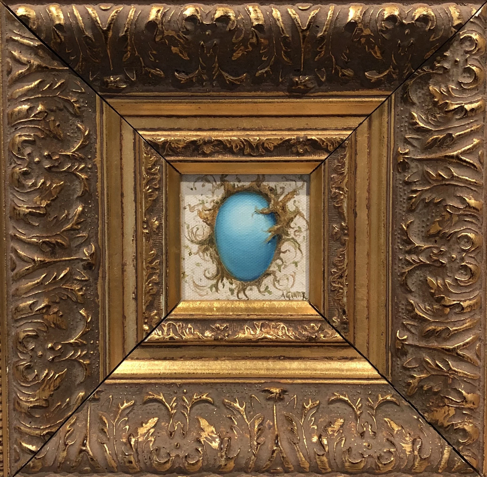 A gold framed oil painting featuring a blue egg with brown branches and swirling patterns surrounding it.