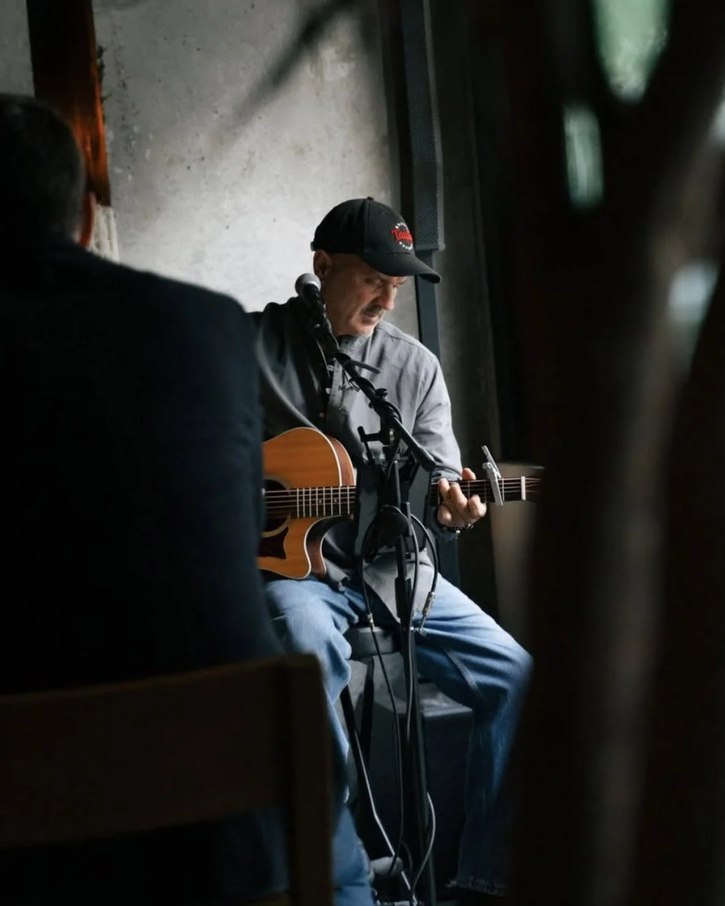 Eric Zobel seated with a guitar in front of a crowd