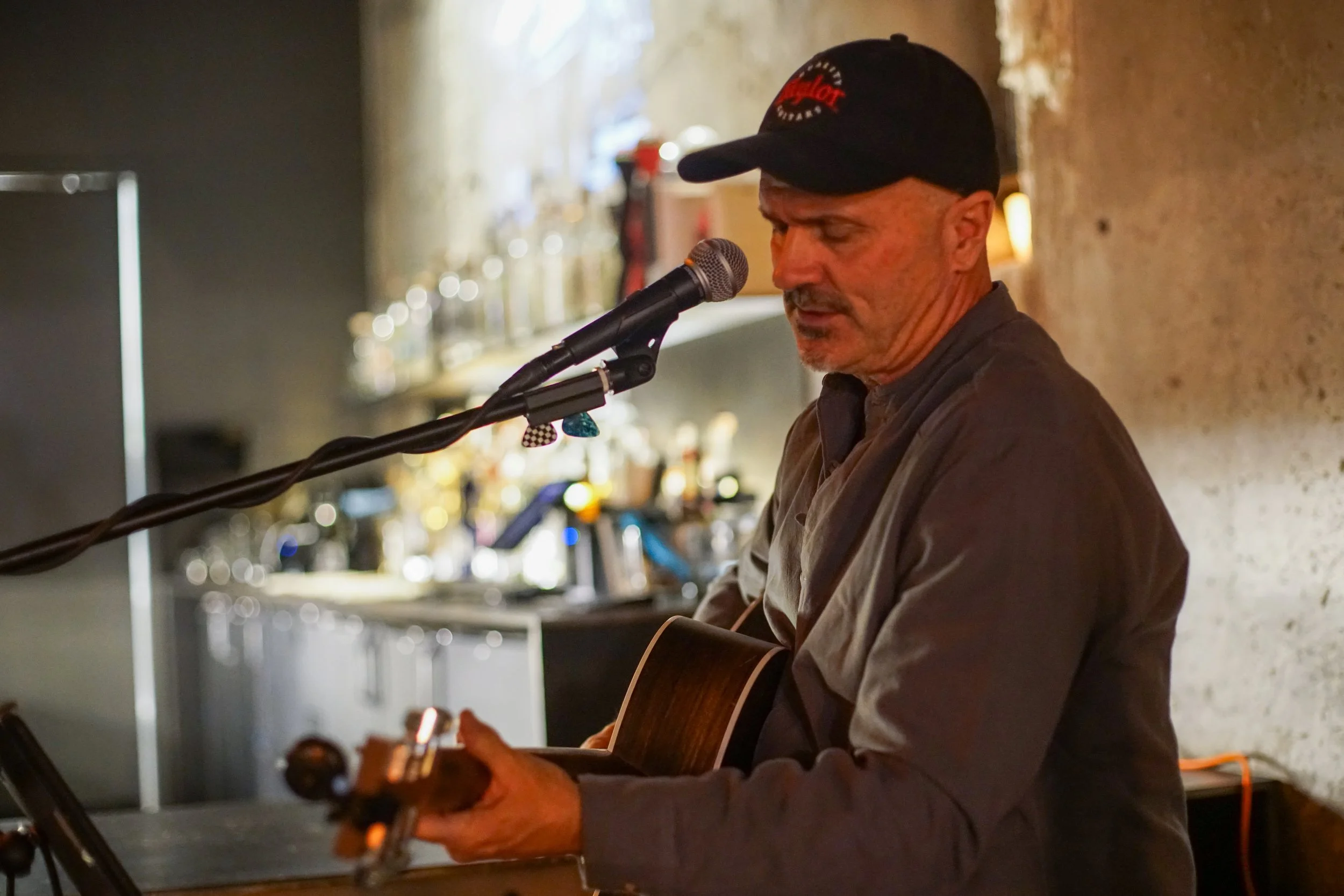 Eric Zobel seated with a guitar singing into a mic