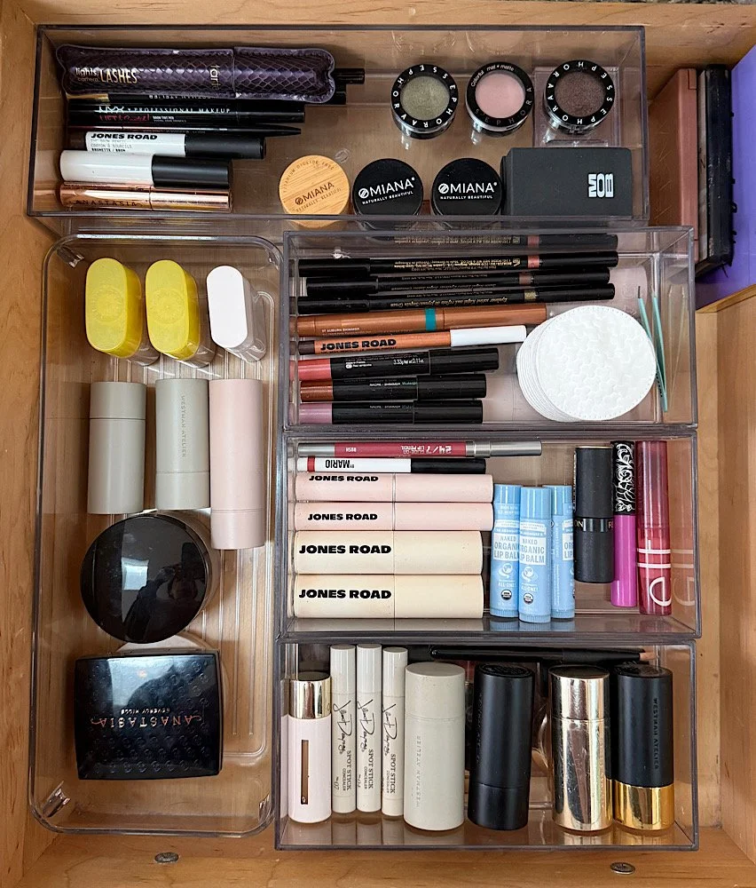 Organized makeup storage drawer with various lip balms, lipsticks, concealers, eyeliners, and skincare products, including brands like Jones Road and MIANA.