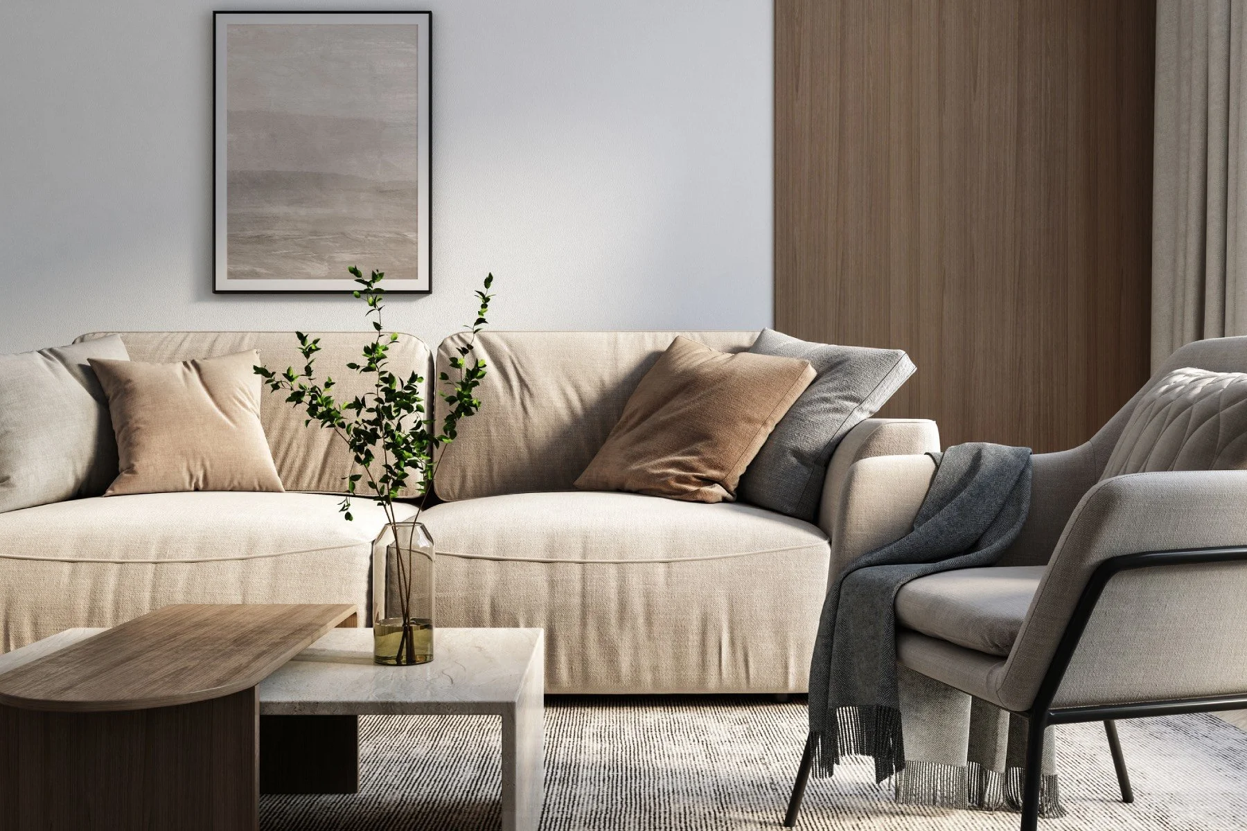 A staged living room for real estate photos and listing. Living room with beige sofa, pillows, a glass vase with green branches, a wooden coffee table, and a gray armchair with a black frame.