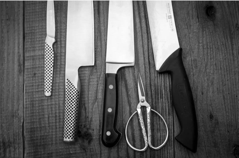 A set of kitchen knives and scissors on a wooden surface.
