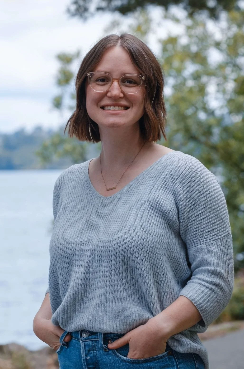 Emily Besaw therapist smiling outside by water and trees