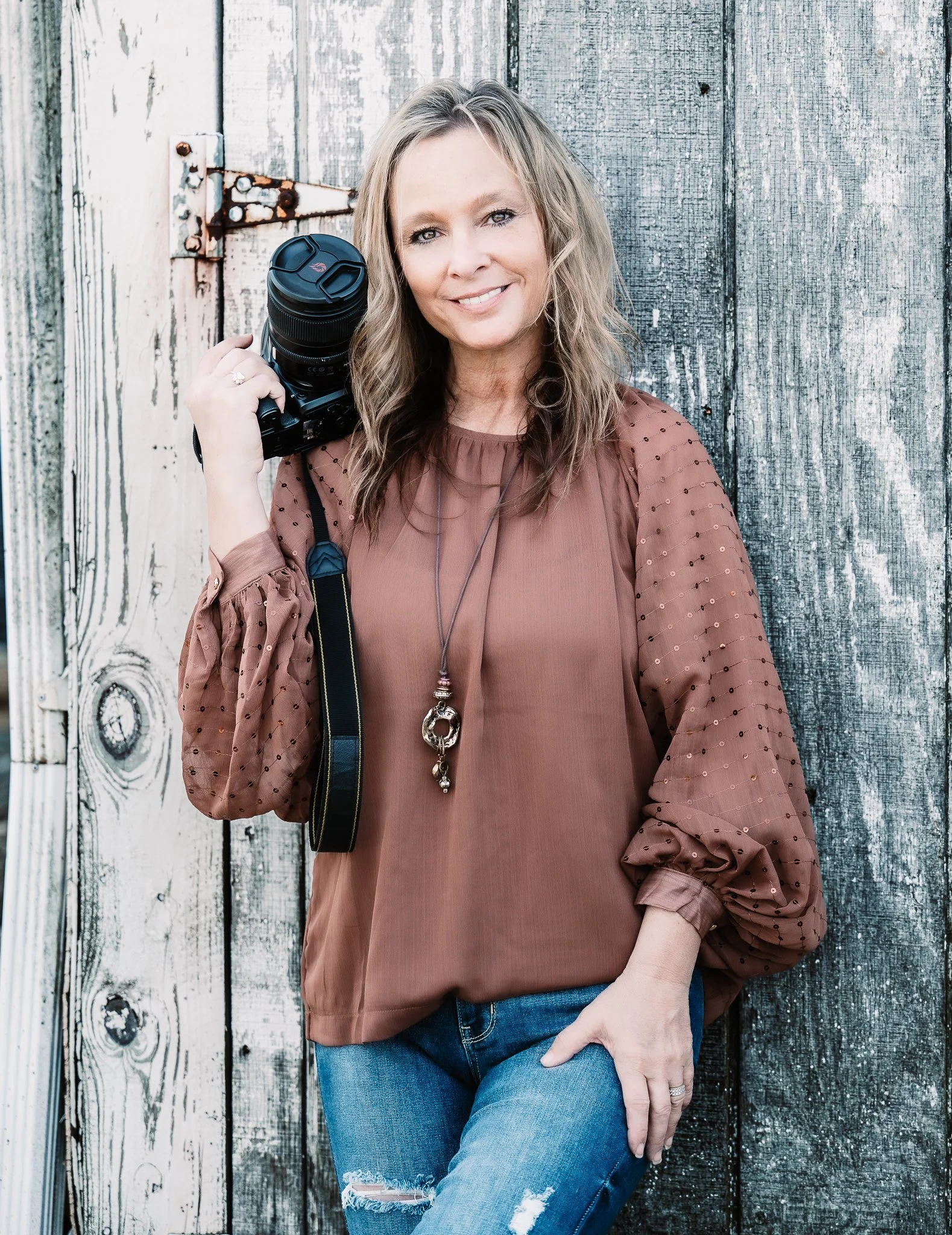 Tracy McKee, Ohio-based portrait photographer specializing in seniors, families, couples, and children, holding her camera outdoors.