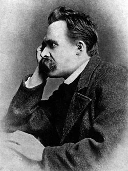 Black and white photo of a man with a beard and mustache, resting his chin on his hand, looking serious.