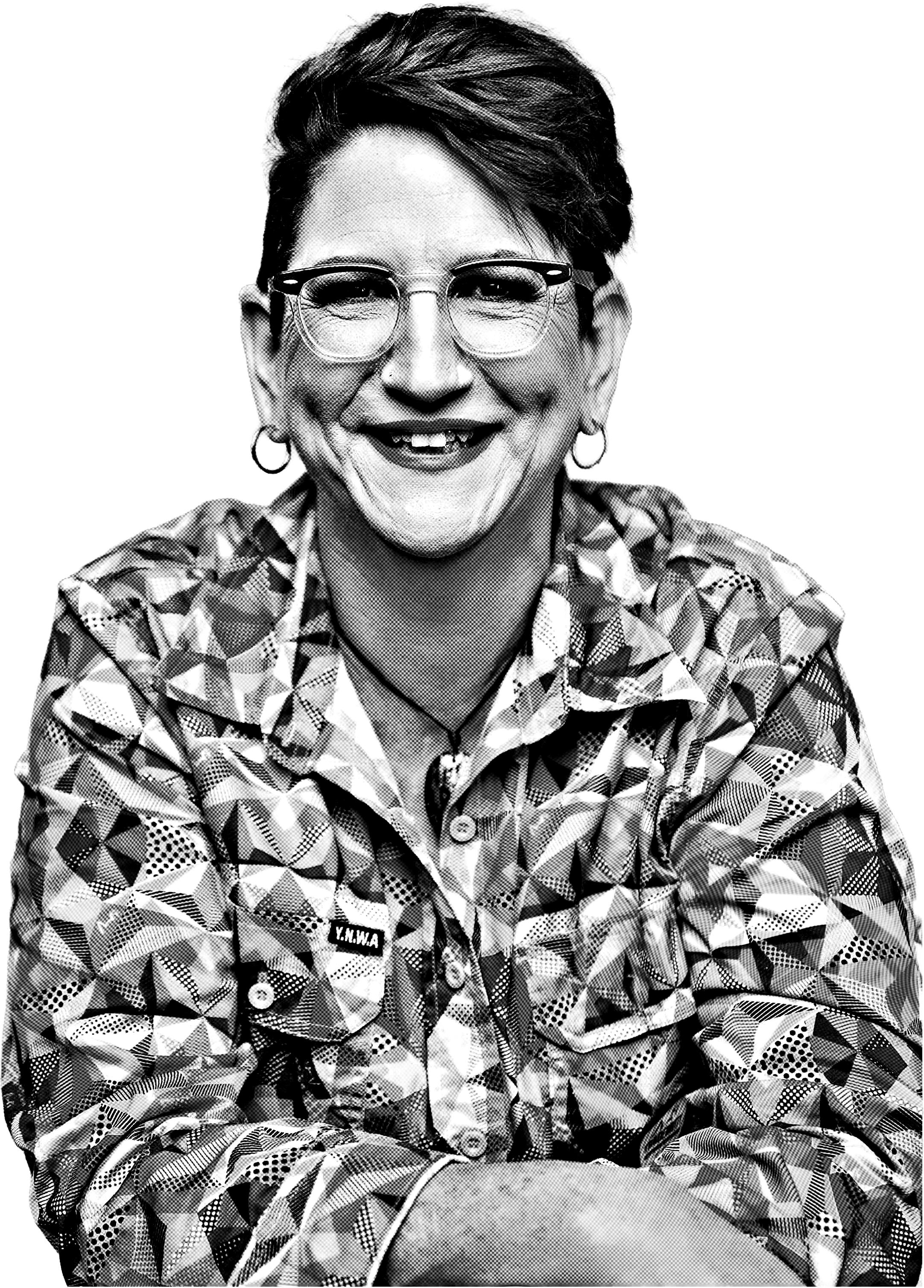 Black and white photo of smiling woman with short hair, glasses, and earrings, wearing a patterned shirt with a badge that reads "Y.N.W.A."